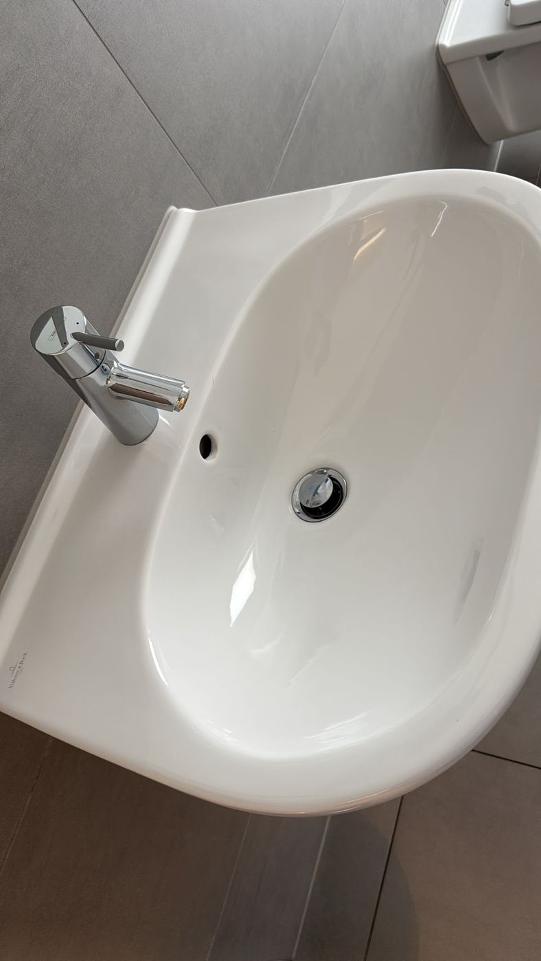 Strahlend sauberes weißes Keramikwaschbecken mit Chromarmatur